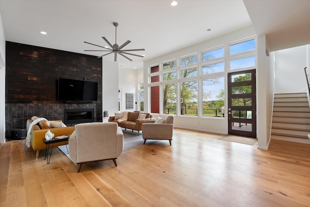 living area with recessed lighting, light wood-style floors, a fireplace, stairway, and a ceiling fan