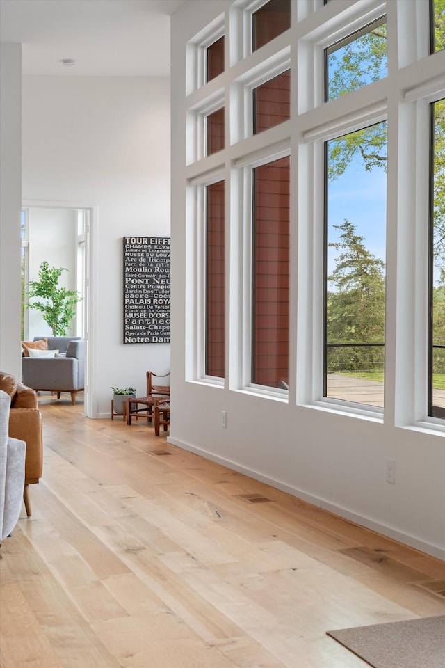 interior space featuring a high ceiling, light wood-style flooring, and baseboards
