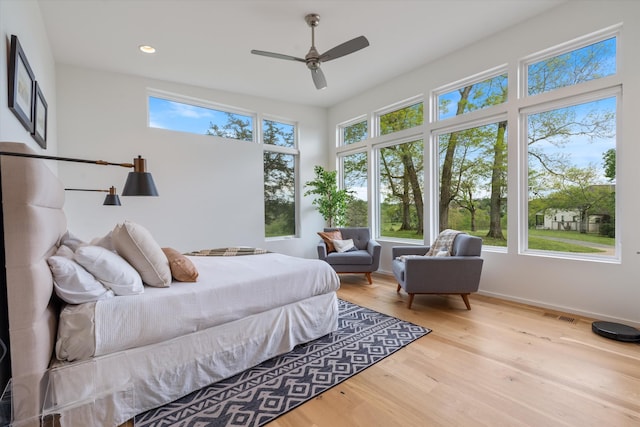 bedroom featuring baseboards, visible vents, wood finished floors, and multiple windows