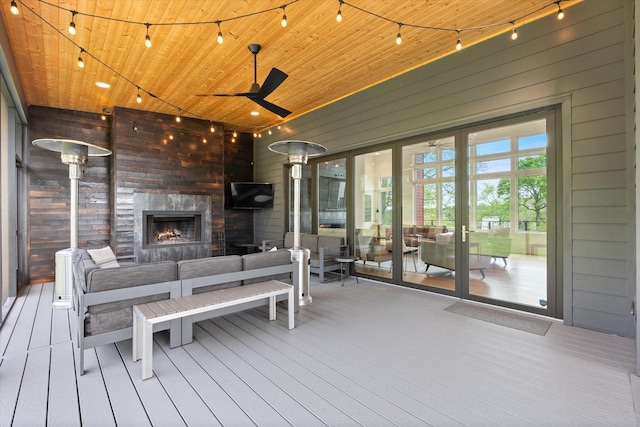 deck featuring a ceiling fan, an outdoor living space with a fireplace, and french doors