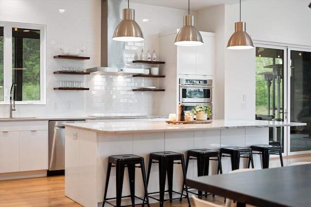 kitchen with a sink, open shelves, backsplash, wall chimney range hood, and white cabinets