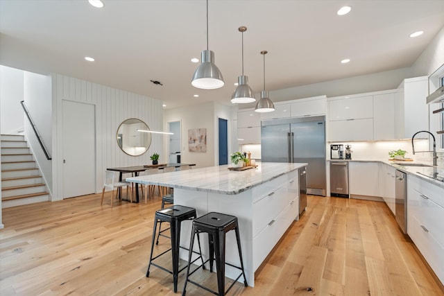 kitchen featuring a sink, modern cabinets, stainless steel appliances, white cabinetry, and a kitchen island