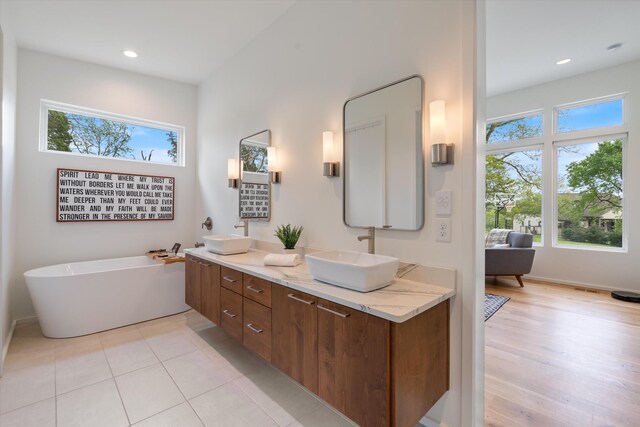 full bath featuring recessed lighting, double vanity, a sink, and a freestanding tub