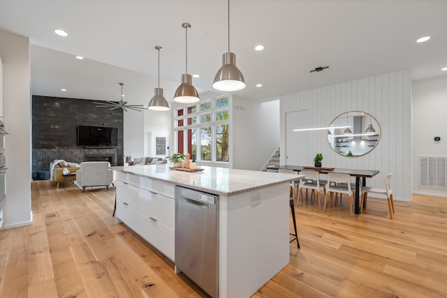 kitchen with white cabinetry, ceiling fan, a large fireplace, a center island, and light wood-type flooring