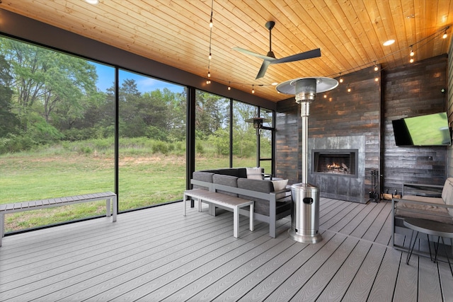 sunroom with a ceiling fan, an outdoor living space with a fireplace, and a wealth of natural light