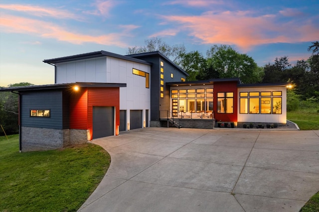 contemporary house with driveway, a yard, and board and batten siding