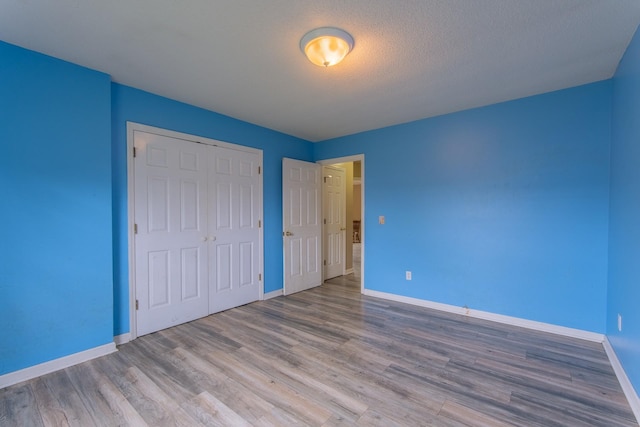 unfurnished bedroom with baseboards, wood finished floors, and a closet