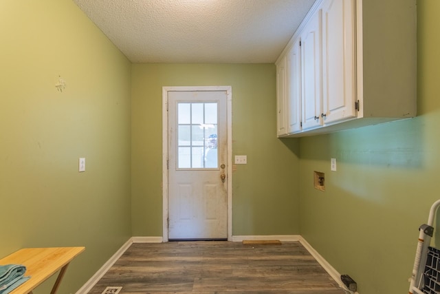clothes washing area featuring cabinet space, dark wood-style flooring, hookup for a washing machine, baseboards, and a textured ceiling