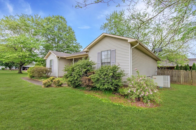 view of side of home with fence, cooling unit, and a lawn