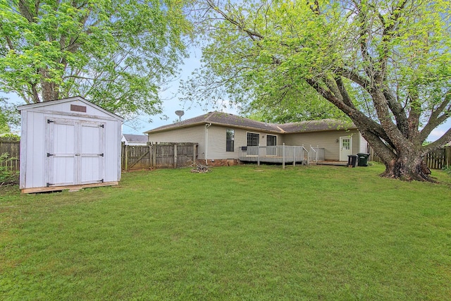 view of yard with a storage unit, a fenced backyard, a wooden deck, and an outbuilding