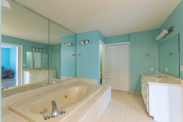 full bathroom featuring baseboards, two vanities, a sink, and a jetted tub