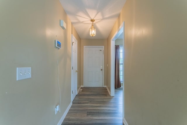 corridor featuring dark wood-style flooring and baseboards