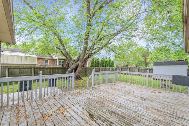 wooden terrace with a storage shed, a lawn, an outdoor structure, and a fenced backyard