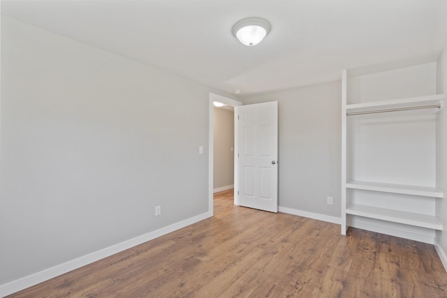 unfurnished bedroom featuring wood finished floors, a closet, and baseboards