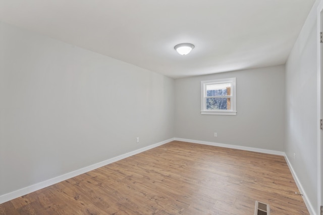 unfurnished room featuring visible vents, light wood-style floors, and baseboards