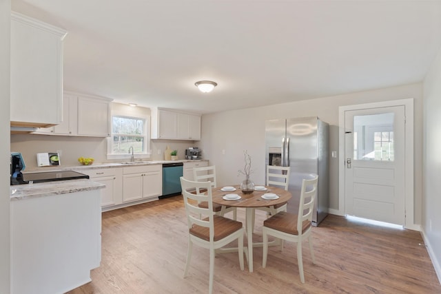 kitchen with white cabinets, a sink, light wood-style floors, dishwashing machine, and stainless steel fridge