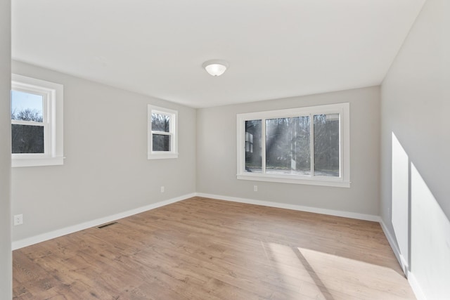 empty room with visible vents, wood finished floors, and baseboards