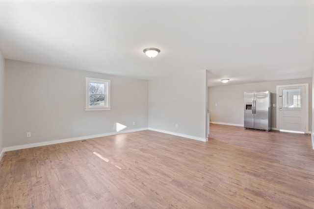 unfurnished living room featuring baseboards, a wealth of natural light, and light wood-type flooring