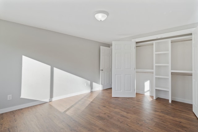 unfurnished bedroom with baseboards, wood finished floors, and a closet