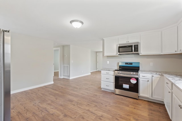 kitchen with light stone counters, white cabinetry, appliances with stainless steel finishes, baseboards, and light wood finished floors