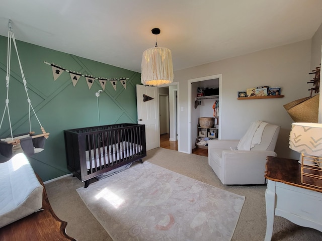 carpeted bedroom with baseboards and a crib