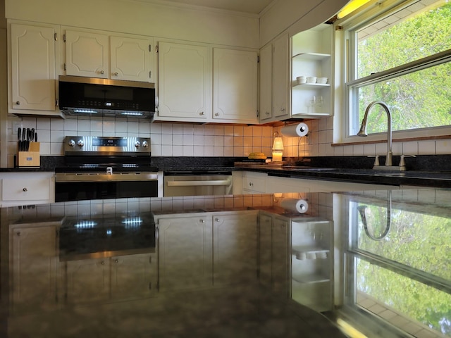 kitchen featuring dark countertops, white cabinets, decorative backsplash, and stainless steel appliances
