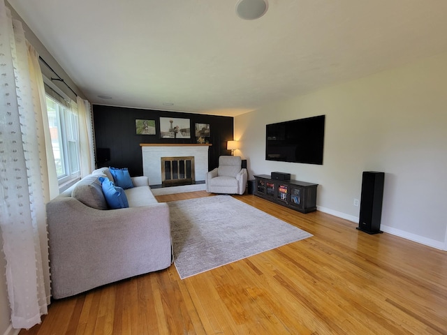 living area with baseboards, wood finished floors, and a fireplace