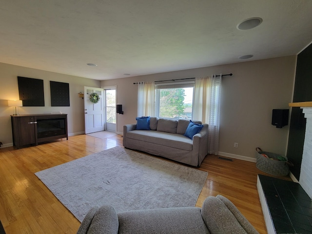 living room with light wood-style floors, baseboards, a fireplace, and visible vents