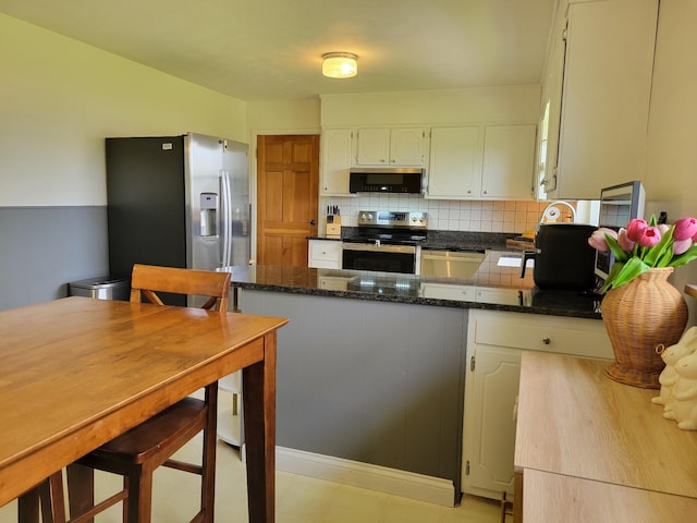 kitchen featuring decorative backsplash, dark stone countertops, appliances with stainless steel finishes, and a peninsula