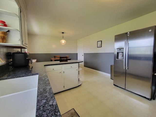 kitchen featuring decorative light fixtures, open shelves, a peninsula, stainless steel fridge, and white cabinetry