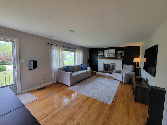 living room with light wood-style floors, baseboards, a fireplace, and visible vents