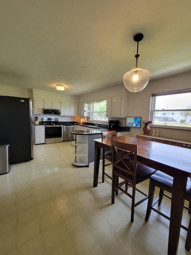 kitchen featuring dark countertops, appliances with stainless steel finishes, white cabinets, and plenty of natural light