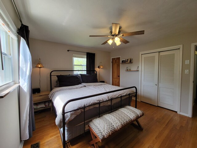 bedroom with visible vents, a ceiling fan, wood finished floors, and a closet