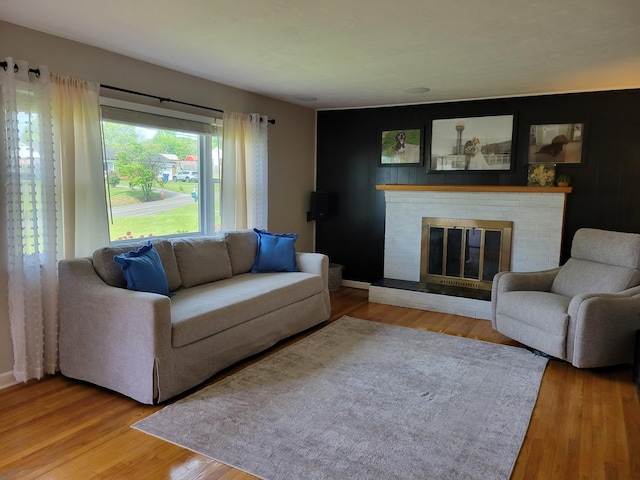 living room featuring baseboards, a brick fireplace, and wood finished floors