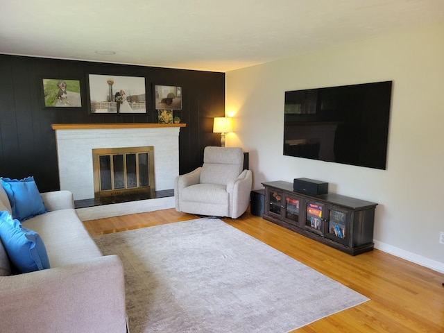 living area featuring baseboards, wood finished floors, and a fireplace