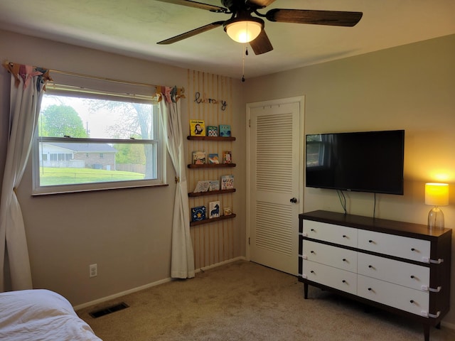 carpeted bedroom with a closet, baseboards, a ceiling fan, and visible vents