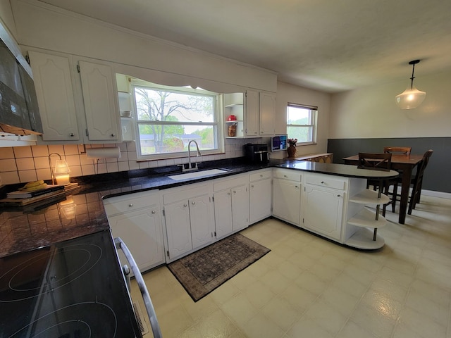 kitchen with open shelves, range with electric cooktop, dark countertops, and a sink