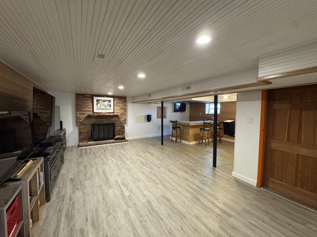 living room with recessed lighting, baseboards, a fireplace, and light wood finished floors