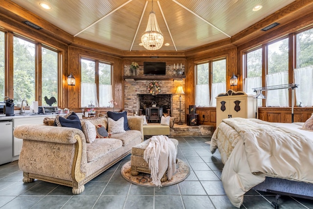 bedroom featuring a wood stove, a sink, a notable chandelier, visible vents, and tile patterned flooring