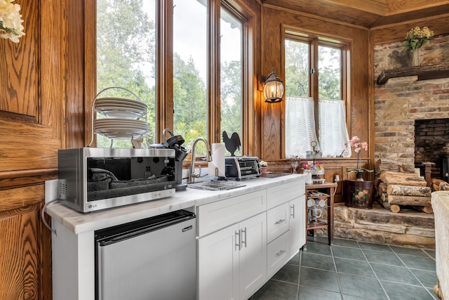 kitchen with dark tile patterned flooring, fridge, stainless steel microwave, light countertops, and white cabinetry