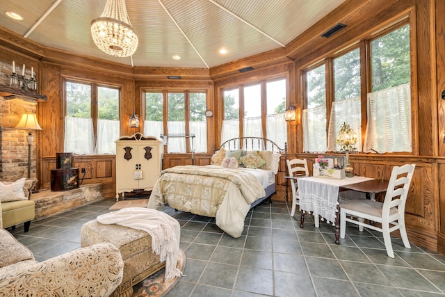 bedroom featuring a wood stove, a chandelier, access to exterior, visible vents, and dark tile patterned flooring
