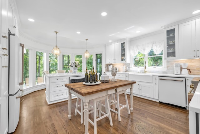 kitchen with white appliances, decorative backsplash, crown molding, and a sink