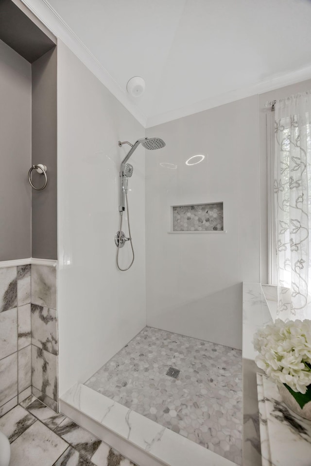 bathroom featuring crown molding, a tile shower, and marble finish floor