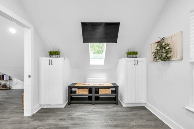 interior space featuring lofted ceiling with skylight, wood finished floors, and baseboards