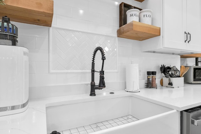 interior details with light countertops, a sink, white cabinetry, and tasteful backsplash