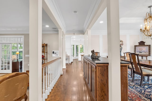 corridor featuring ornamental molding, dark wood-type flooring, a chandelier, and a healthy amount of sunlight