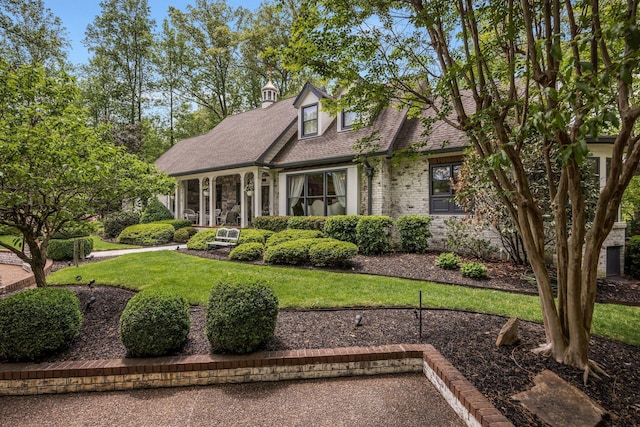 cape cod home featuring a front lawn and roof with shingles