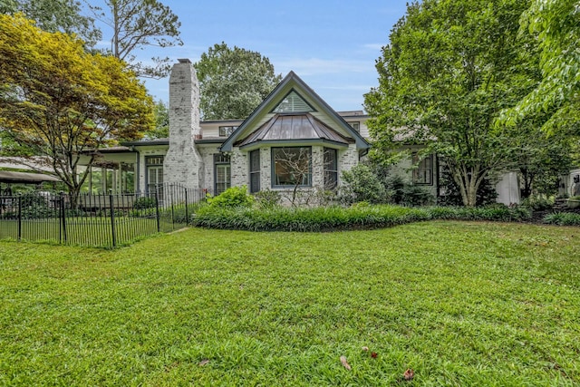 tudor-style house with a chimney, fence, and a front lawn