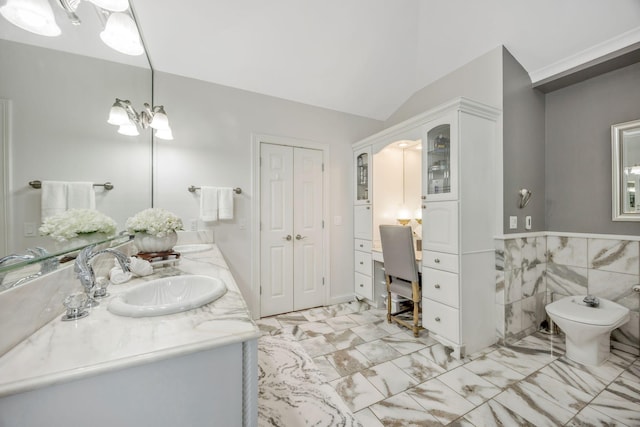 full bath with double vanity, vaulted ceiling, marble finish floor, a wainscoted wall, and a sink