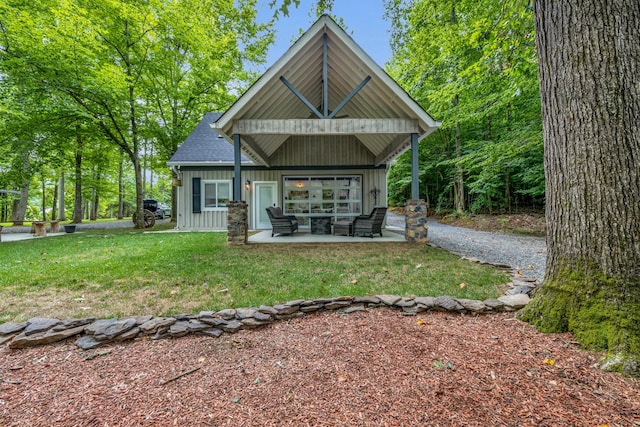 rear view of house with a lawn, roof with shingles, board and batten siding, and a patio area